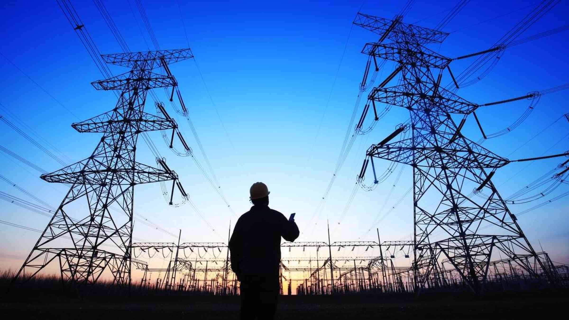 An engineer observes transmission lines overhead