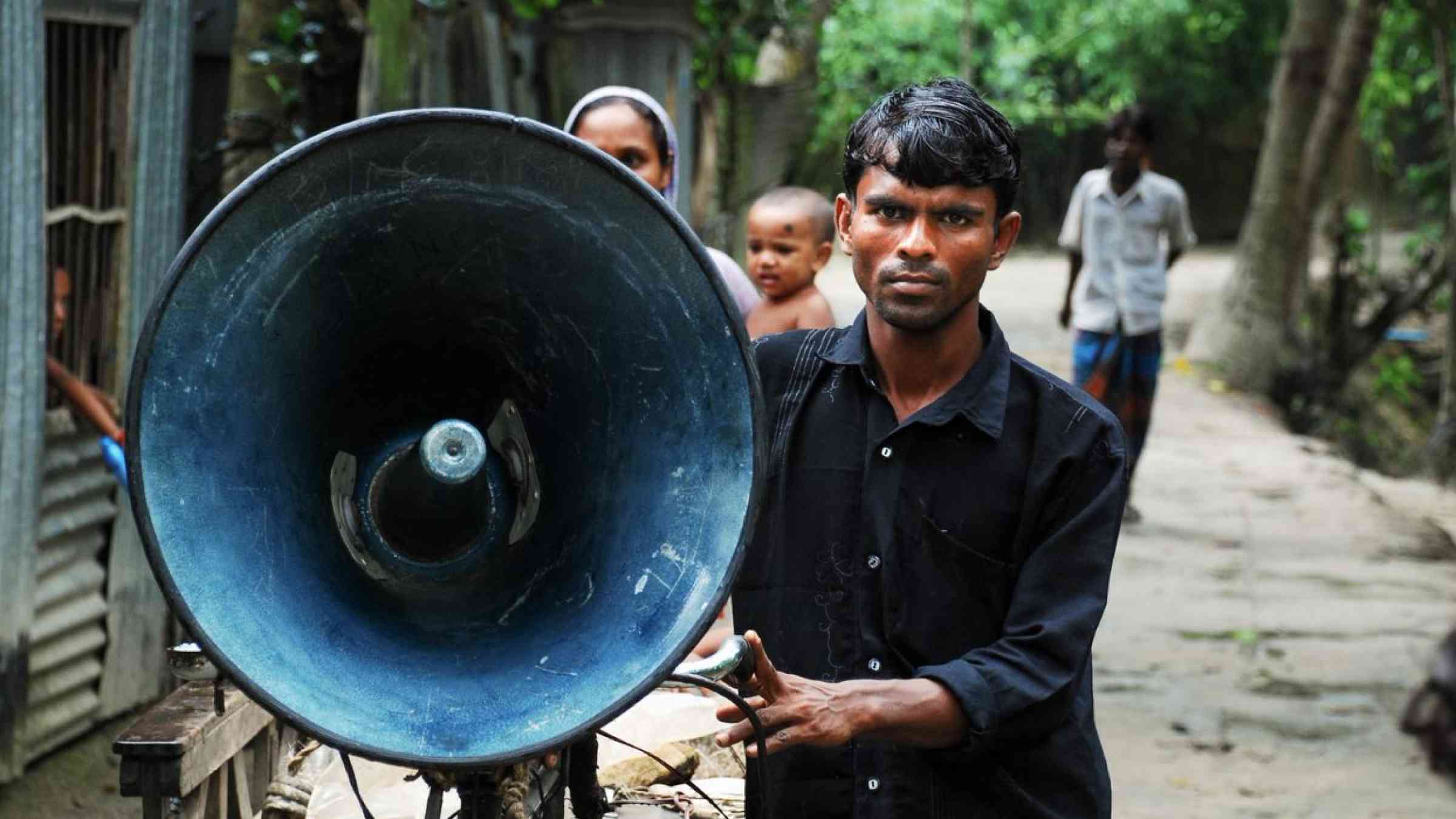 Man holding a loud speaker for early warning in Bangladesh.