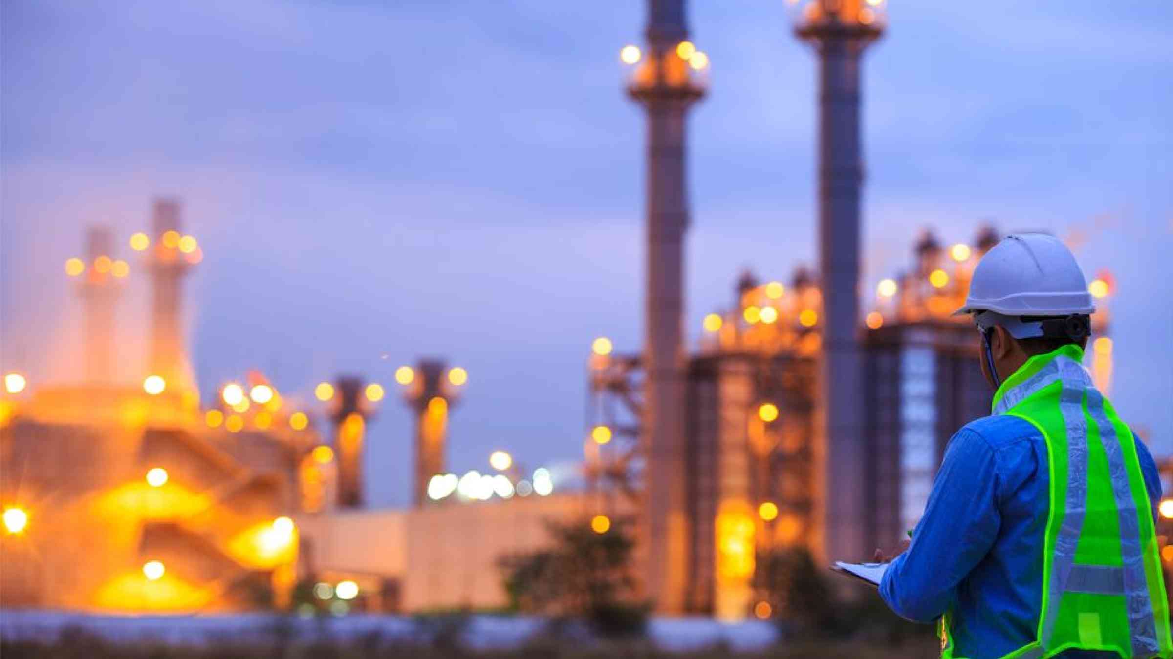 person in work safety clothing looking at a industrial facility