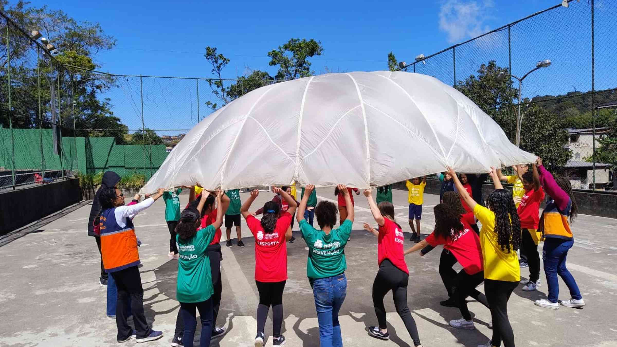 Children walking with open umbrellas in a disaster risk prevention drill at a school in Petrópolis.