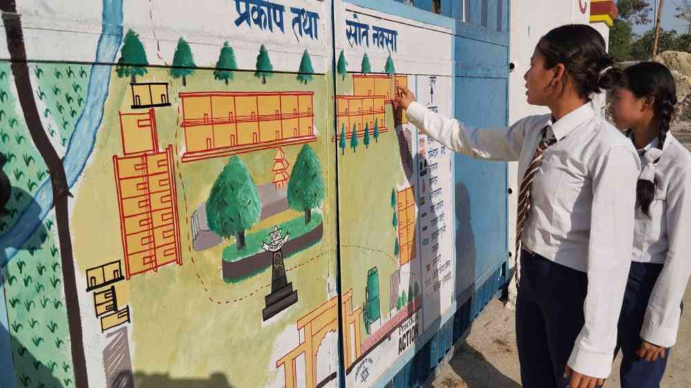 Students in Nepal examine a hazard-related mural at their school