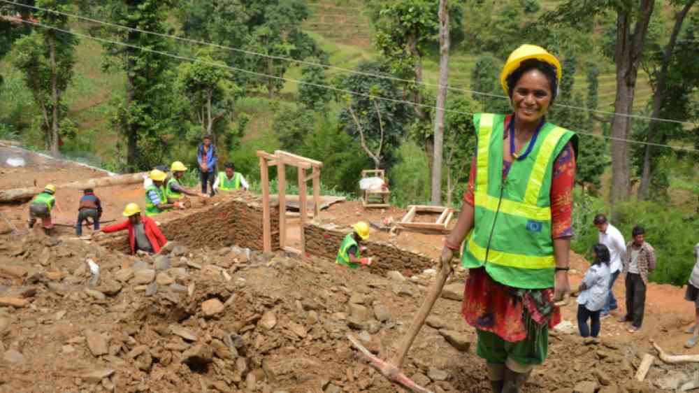 Female construction worker building house with community