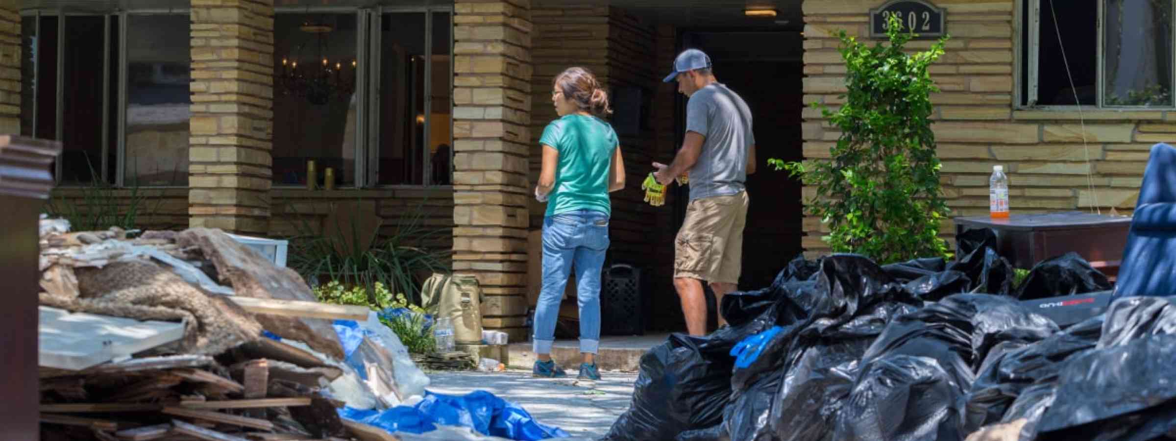 Homeowners in front of their house after floods.